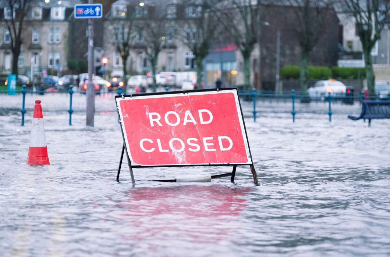 A road closed sign partially submerged in flood water